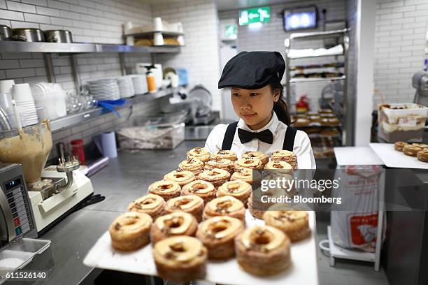 An employee carries a tray of freshly made Cronuts during the opening of the Dominique Ansel Bakery in London, U.K., on Friday, Sept. 30, 2016. The...