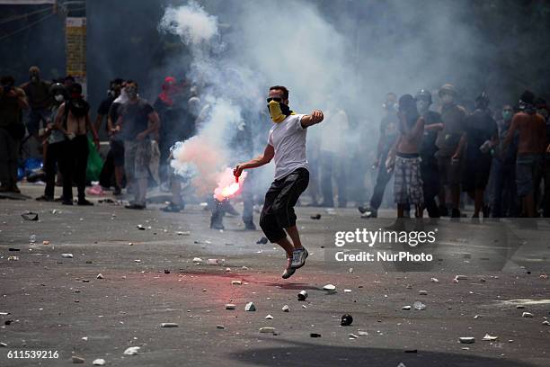 Protester throws a flare. Demonstrations in Athens against austerity. Another massive demonstration against the government 's plans for new austerity...