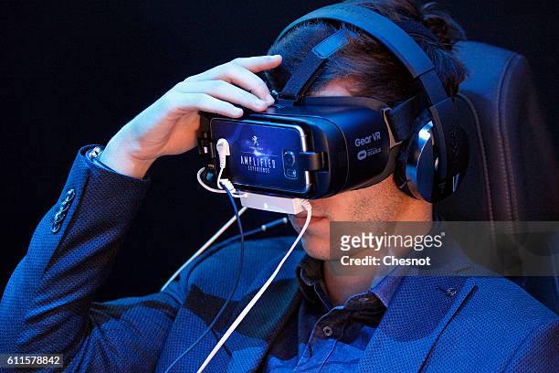 Visitor plays a game with the virtual reality head-mounted Gear VR powered by Oculus during the second press day of the Paris Motor Show on September...