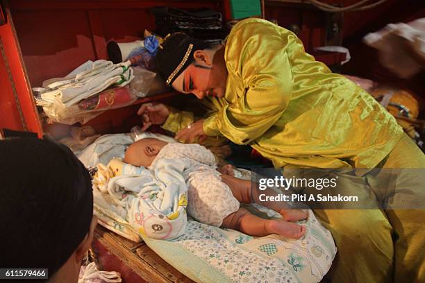 Chinese opera performer taking care of a baby on backstage before performing at A Chinese shrine during the vegetarian festival 2016 in Bangkok's...