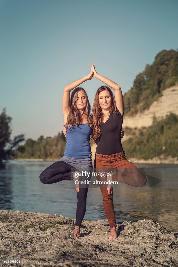 Two women at a river yoga pose