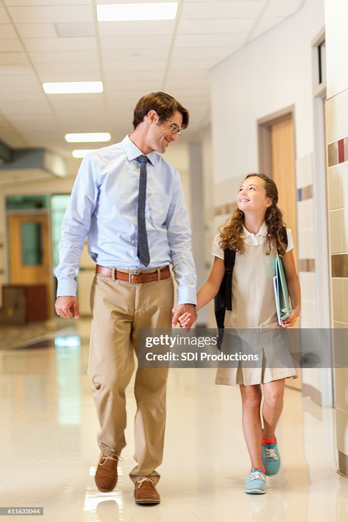 Father and daughter walking together to elementary school classroom