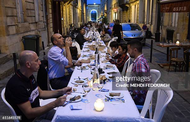 People eat and drink during the wine harvesting festival "La rue gourmande" in Bordeaux, southwestern France, on September 30, 2016. The festival was...