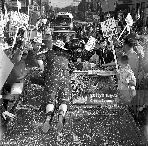 Risking a run in her stocking, this enthusiastic woman sprawls across the hood of the car, determined to get as close as she can to the Democractic...