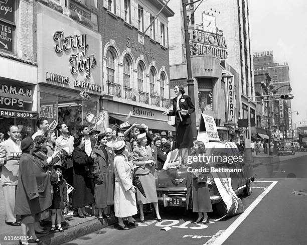 Dorothy Dimm, an Eisenhower for President worker, distributes pamphlets and buttons from atop a campaign car on Broad Street in Newark. Ike forces...