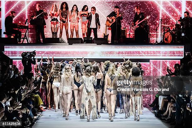 Models walk the runway while singer Jacques Dutronc performs on stage during the Etam show as part of the Paris Fashion Week Womenswear Spring/Summer...