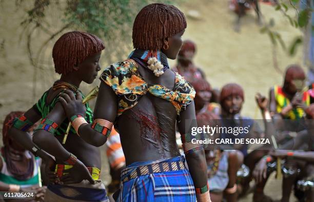 Hamar women bearing scars and blood from whipping on their backs stand before a bull jumping ceremony in Ethiopia's southern Omo Valley region near...