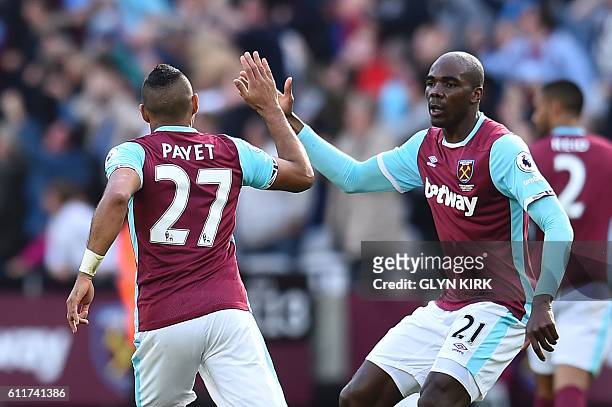 West Ham United's French midfielder Dimitri Payet high-fives West Ham United's Italian defender Angelo Ogbonna after scoring their first goal to...