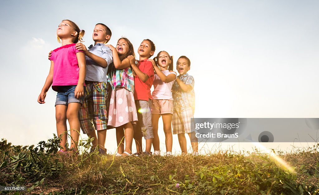 Below view of children standing in a row and singing.