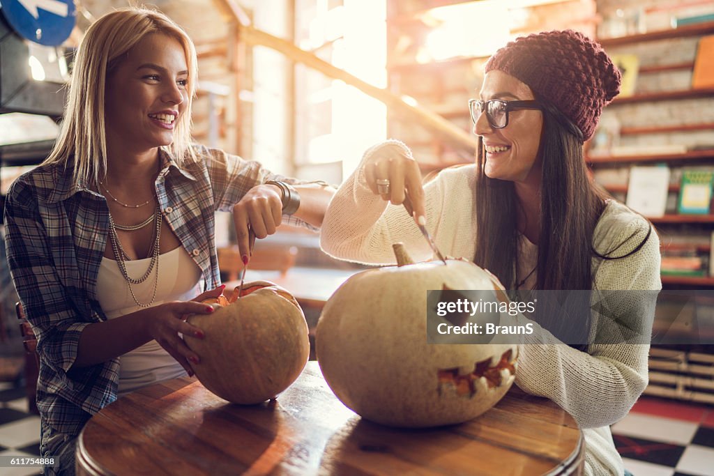 Amici sorridenti che comunicano mentre intaglio le zucche per Halloween.