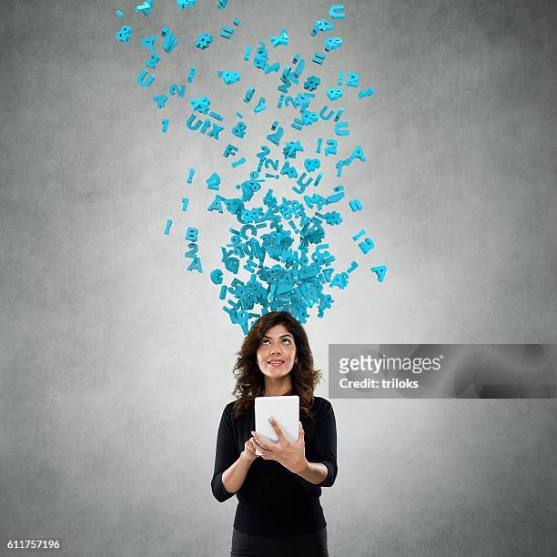 businesswoman using digital tablet with flying alphabets - medium group of people stockfoto's en -beelden