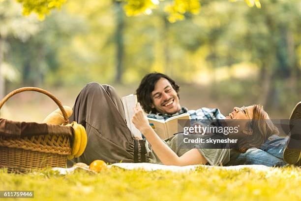 happy couple laughing while reading book at picnic. - romantic picnic stockfoto's en -beelden