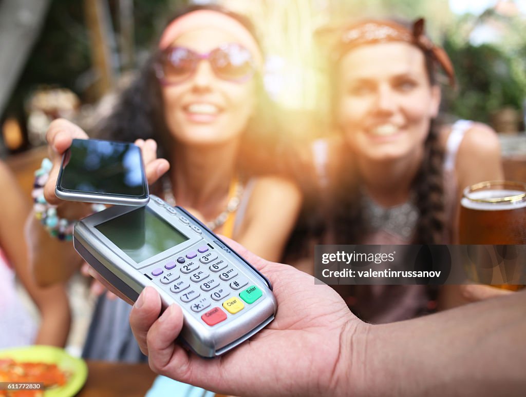 Frau mit ihrem Smartphone für mobiles Bezahlen im Restaurant