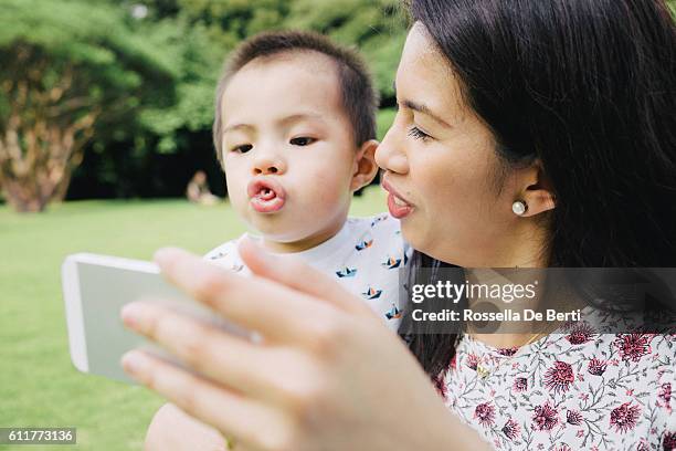 mother and son taking selfie picture with smartphone outdoors - funny face baby stock pictures, royalty-free photos & images