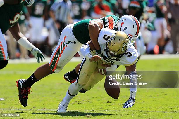 Justin Thomas of the Georgia Tech Yellow Jackets fumbles after being sacked by Trent Harris of the Miami Hurricanes during the first half at Bobby...