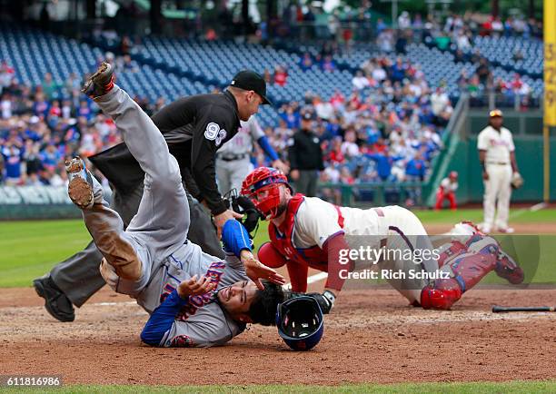 Travis d'Arnaud of the New York Mets tumbles after scoring before the tag of catcher Cameron Rupp of the Philadelphia Phillies on a double by Jose...