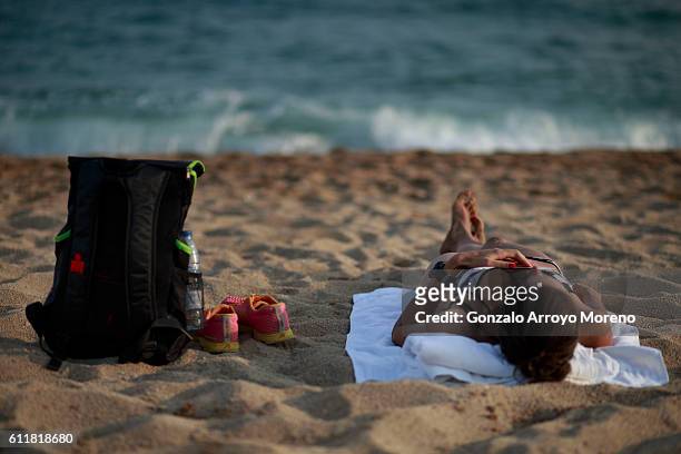 Woman lies on the beach close to an Ironman Barcelona bag the day before of the Ironman Barcelona on October 1, 2016 in Calella, Spain.
