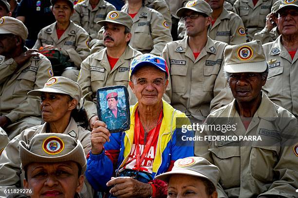 Suppporter of Venezuelan President Nicolas Maduro holds a portrait of late Venezuelan President Hugo Chavez during the commemoration of the 2nd...