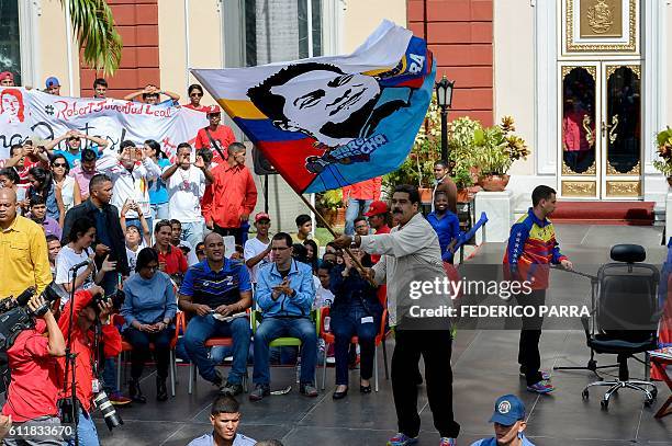 Venezuelan President Nicolas Maduro waves a flag which depicts late deputy Robert Serra during the commemoration of the 2nd anniversary of the death...