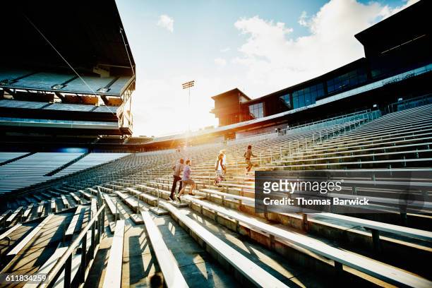 athletes running stairs in empty stadium at sunset - forward athlete stockfoto's en -beelden