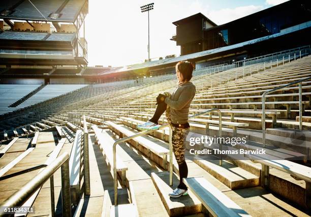 athlete stretching before workout in stadium - hand on knee fotografías e imágenes de stock