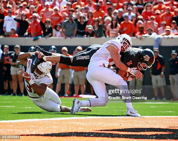 Quarterback Mason Rudolph of the Oklahoma State Cowboys is hit by safety Dylan Haines and safety Jason Hall of the Texas Longhorns on his way to...