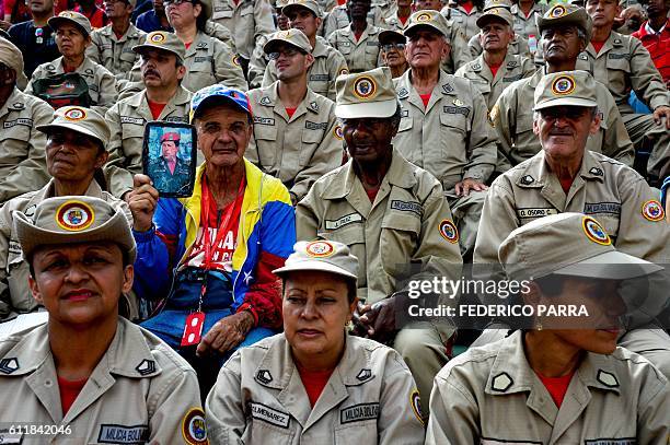 Suppporter of Venezuelan President Nicolas Maduro holds a portrait of late Venezuelan President Hugo Chavez during the commemoration of the 2nd...