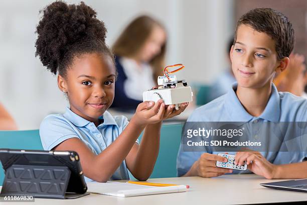 proud african american schoolgirl holds up robot - african american school uniform stock pictures, royalty-free photos & images