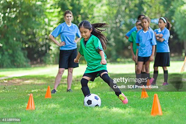 elementary age soccer athlete kicks ball around cones - schoppen lichaamsbeweging stockfoto's en -beelden