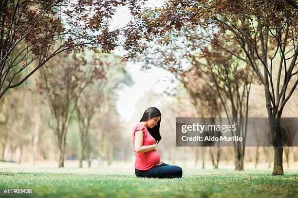 side view of pregnant woman sitting and holding belly - woman smiling facing down stock pictures, royalty-free photos & images