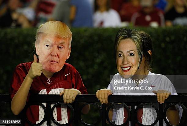 Two fans are seen wearing masks of 2016 presidential candidates Donald Trump and Hillary Clinton during the game between the Alabama Crimson Tide and...