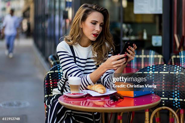 German model and fashion blogger Alexandra Lapp sitting in a French Cafe drinking coffee and eating Croissant wearing striped jumper from Steffen...