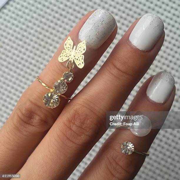 fingers with rings on it showing white nail polish on fingernail - white nail polish stockfoto's en -beelden