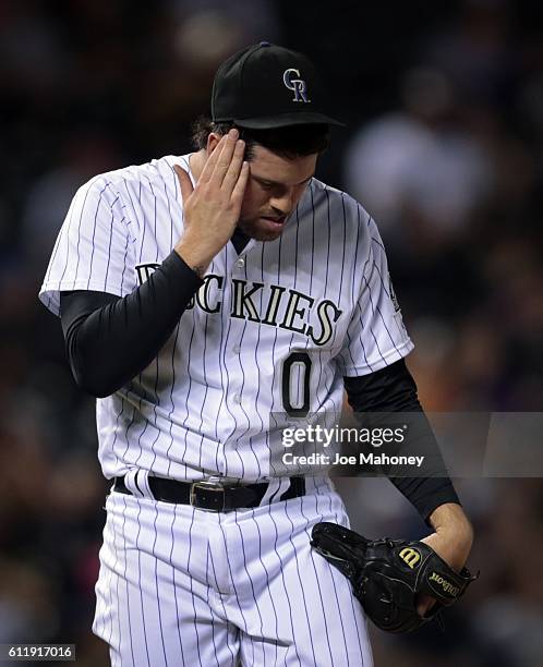 Pitcher Adam Ottavino of the Colorado Rockies wipes his head after Chris Carter of the Milwaukee Brewers hit the game-winning home run in the 10th...