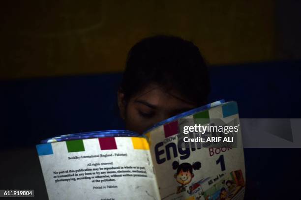 In this photograph taken on September 27 Esha Masih, daughter of Asia Bibi, a Christian woman facing death sentence for blasphemy, reads a book at a...