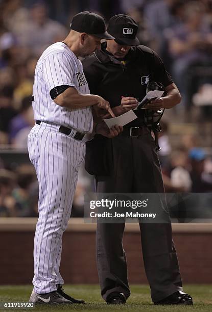 Walt Weiss of the Colorado Rockies, left, presents a defensive change to umpire Roberto Ortiz in the eighth inning against the Milwaukee Brewers at...