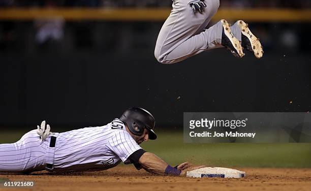 Daniel Descalso of the Colorado Rockies dives safely back to second base as Orlando Arcia of the Milwaukee Brewers hops over the base in the eighth...