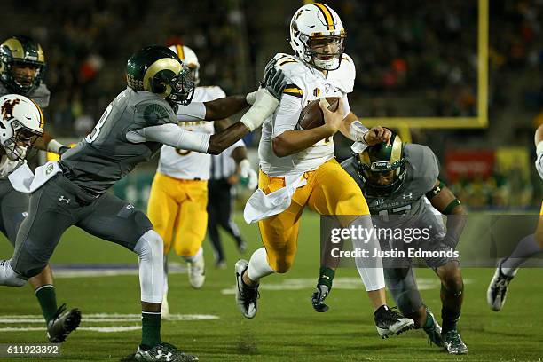 Quarterback Josh Allen of the Wyoming Cowboys splits the defense of defensive back Braylin Scott and defensive back Shun Johnson of the Colorado...