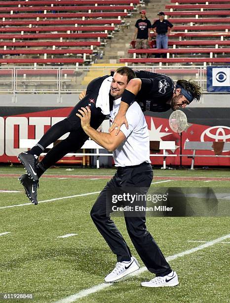 Graduate assistant coach Ben Cotton of the UNLV Rebels picks up and spins quarterback Dalton Sneed of the Rebels on the field after the team's 45-20...