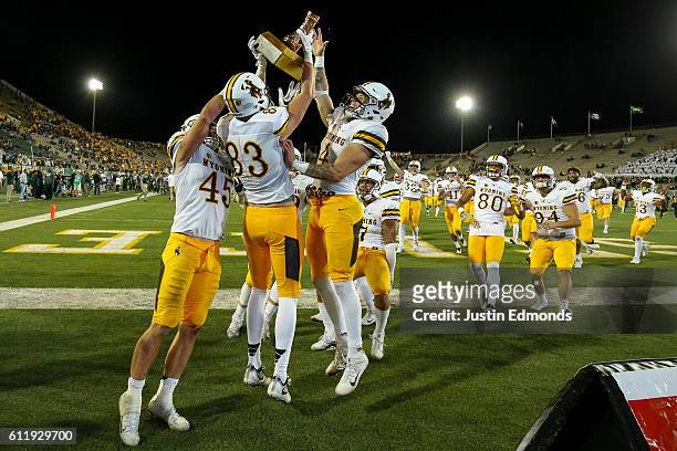 Wide receiver Jake Maulhardt of the Wyoming Cowboys hoists The Bronze Boot and celebrates with his teammates after defeating Colorado State Rams...