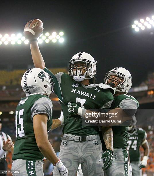 Metuisela `Unga of the Hawai'I Rainbow Warriors holds the football high as he is congratulated by his teammates after making a touchdown reception...