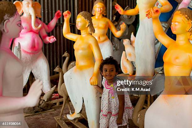 Girl stands where Bangladeshi artists make preparation for the upcoming Durga Puja festival at old Dhaka, Bangladesh. Bengalis all over the world...