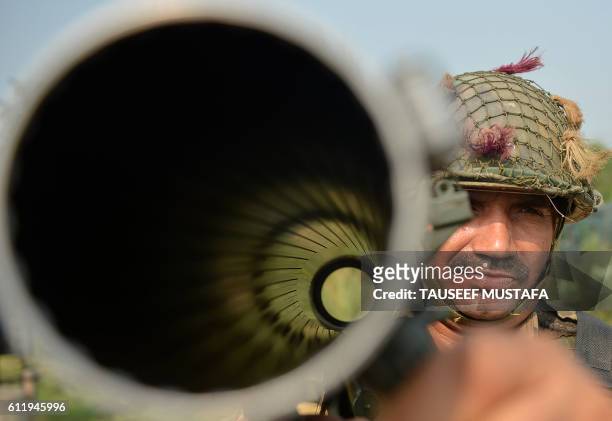 An Indian Border Security Force soldier carries a rocket launcher as he takes up position with colleagues at an outpost along a fence at the...