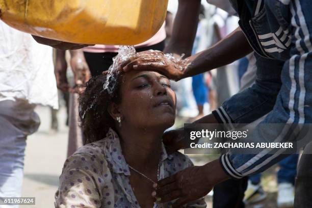 Men wash the face of a woman after police used teargas during the Oromo new year holiday Irreechaa in Bishoftu on October 2, 2016. Several people...