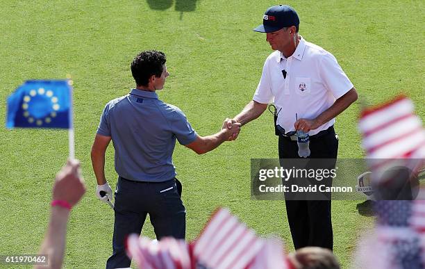 Rory McIlroy of Europe shakes hands with captain Davis Love III of the United States on the first tee during singles matches of the 2016 Ryder Cup at...