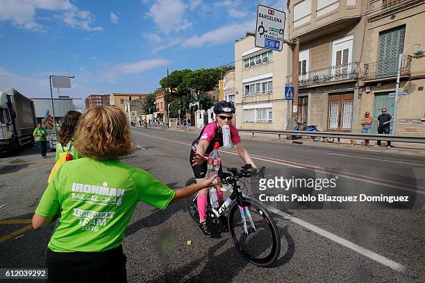 An athlete grabs a bottle of water from volunteer at a food station during the bike leg of Ironman Barcelona on October 2, 2016 near Calella, in...