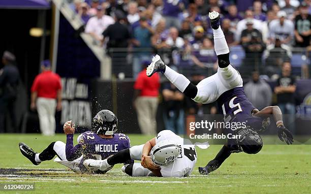 Derek Carr of the Oakland Raiders dives between C.J. Mosley and Eric Weddle of the Baltimore Ravens in the second quarter at M&T Bank Stadium on...