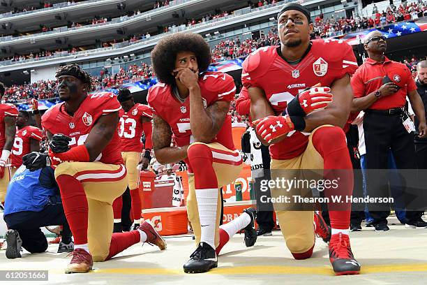 Eli Harold, Colin Kaepernick and Eric Reid of the San Francisco 49ers kneel on the sideline during the anthem prior to the game against the Dallas...