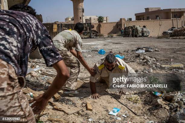 Fighters loyal to Libya's Government of National Accord help a wounded comrade after he was shot by an Islamic State group sniper on the western...