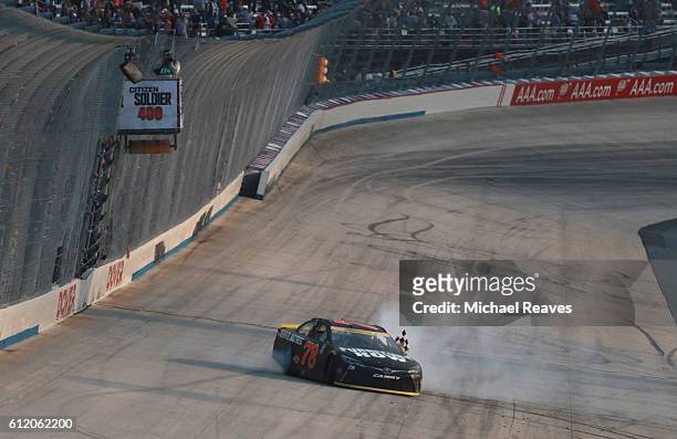 Martin Truex Jr., driver of the Furniture Row/Denver Mattress Toyota, celebrates with the checkered flag after winning the NASCAR Sprint Cup Series...